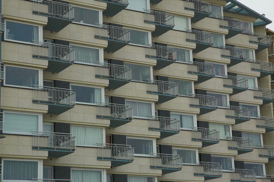 Contemporary urban residential building facade with multiple balconies and windows.