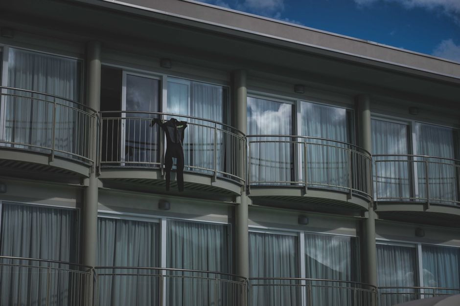 Small black jumpsuit on simple railing of balcony of modern multi storey building under blue sky in daytime